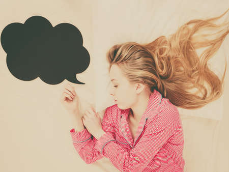 Teenage sleepwear fashion concept. Young woman lying on bed wearing cute pink pajamas, black...