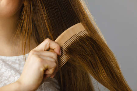 Haircare and morning hairstyling concept. Happy woman brushing her long dark brown hair