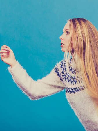 Running away from something concept. Woman with long blonde hair running. Studio shot on blue...