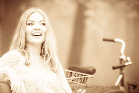 Autumn concept, people outside, spare time. Attractive woman sitting on the bench. Girl is relaxing in the park in autumnal weather.の写真素材