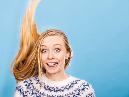 Hairstyles ideas, happiness concept. Crazy teenage woman wearing winter jumper with windblown blonde...