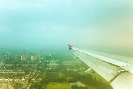 Adventure, travel, transport concept. View from plane window at sky with clouds, wing and cityの写真素材