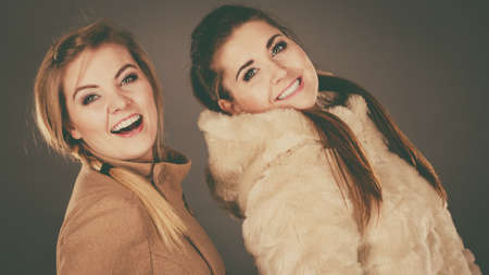 Two women, wearing light brown coat and furry jacket. Winter fashion concept.の写真素材