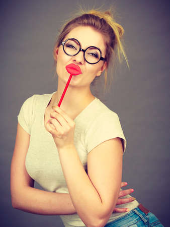 Happy woman holding carnival accessoies on stick having fun wearing white shirtの写真素材