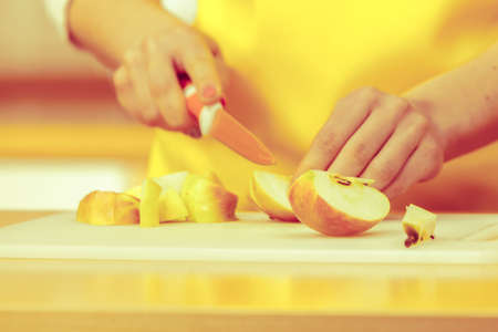 Woman young housewife in kitchen at home preparing fresh salad slicing apple fruits on cutting board. Healthy eating, cooking, vegetarian food, dieting and people conceptの写真素材