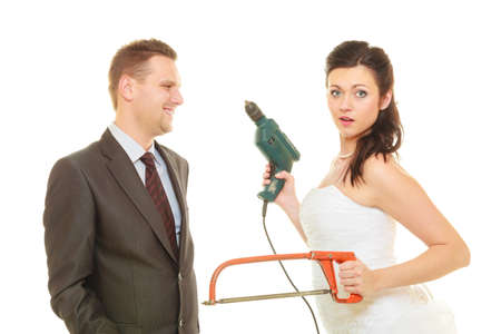 Taking care of house together, sharing household duties concept. Bride in wedding dress and groom wearing elegant suit holding cleaning equipment and tools.の写真素材