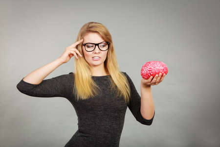 Intellectual expressions, being focused concept. Closeup of attractive woman thinking face expression holding brainの写真素材