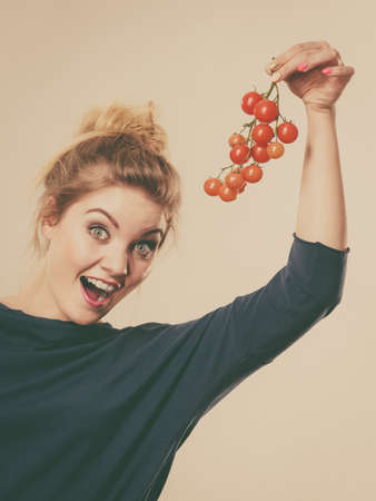 Organic vegetables and food concept. Happy positive smiling woman holding fresh cherry tomatoesの写真素材