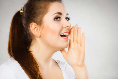 Woman talking to someone gossip and rumors with hand close to lips.