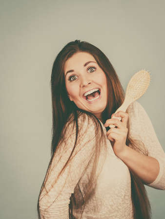 Haircare and morning hairstyling concept. Happy woman brushing her long dark brown hairの写真素材