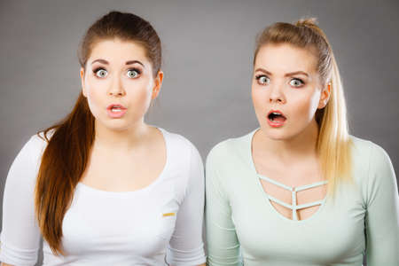 Shock face expressions concept. Closeup of two shocked and amazed women seeing something weird.の写真素材