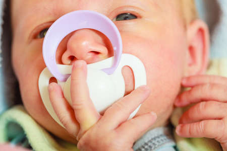 Infant care, beauty of childhood concept. Little newborn baby lying calmly in bed with teat in...