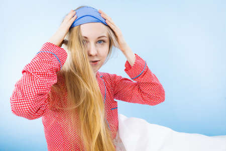 Young woman wearing cute pink pajamas putting sleeping eye bandの写真素材