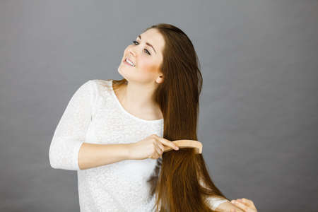 Haircare and morning hairstyling concept. Happy woman brushing her long dark brown hairの写真素材