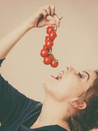 Organic vegetables and food concept. Happy positive smiling woman holding fresh cherry tomatoesの写真素材