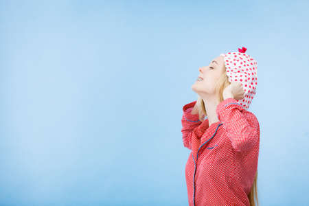 Young woman wearing cute pink pajamas putting bathing cap on her head.の写真素材