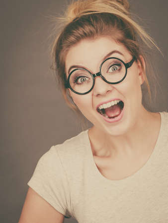Happy blonde teenage woman wearing nerdy eyeglasses, white t shirt. Teenager fashion concept.の写真素材