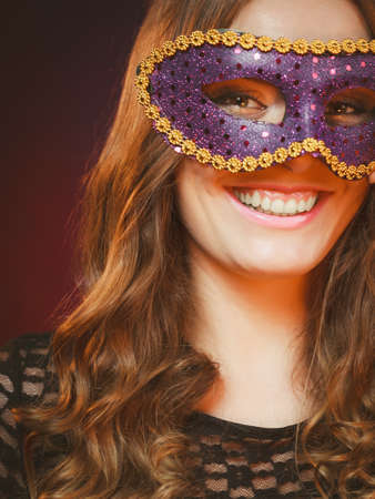 Holidays, people and celebration concept. Closeup woman face with carnival violet mask on dark background.の写真素材
