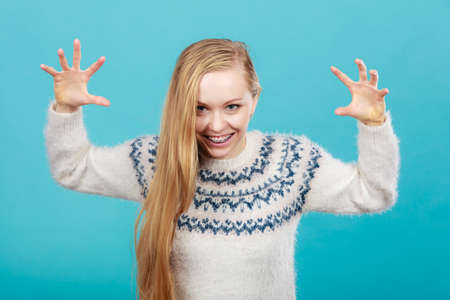 Fooling around concept. Young blonde teenage woman making scary faces to frighten someone for fun.の写真素材