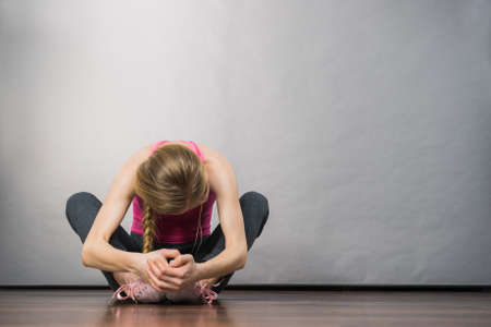 Sad depressed young teenage girl sitting by wall hiding face. School, adolescence, home violence, unwanted love problems.の写真素材