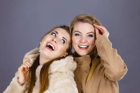 Two women, wearing light brown coat and furry jacket. Winter fashion concept.の写真素材