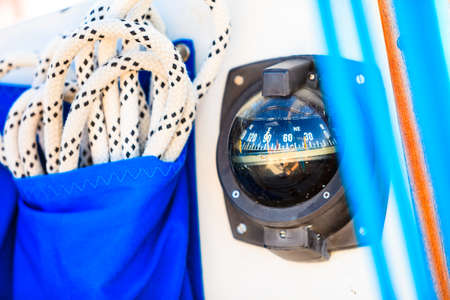 Detailed closeup of rigging and compass on sail boat during cruise. Marine objects concept.