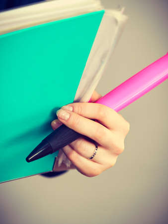 Woman hand holding blue binder with many documents and pen. Office, bookkeeping objects concept.の写真素材