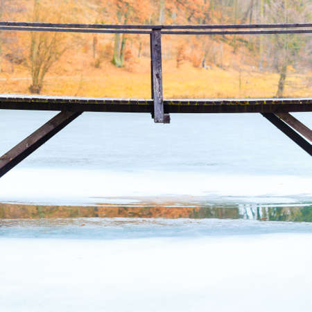 Landscapes, objects, beauty of nature concept. Old, wooden, small bridge on frozen lake, sunny chilly day.の写真素材