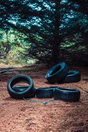 Many old car tires lying in dark forest. Environmental pollution, illegal landfills concept.の写真素材