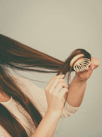 Haircare and morning hairstyling concept. Happy woman brushing her long dark brown hairの写真素材