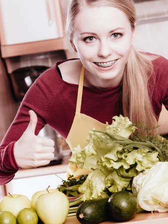 Young woman in kitchen having many green vegetables about to cook something healthy and vegetarianの写真素材
