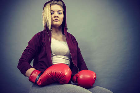 Sporty woman wearing red boxing gloves, getting ready for fight. Studio shot on dark background.の写真素材