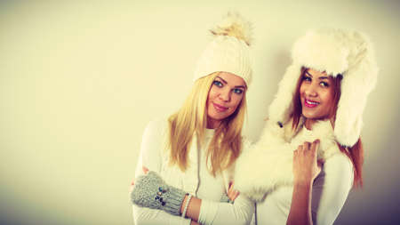 Fashion models people concept. Two women with winter clothes. Blonde and mixed race ladies wearing warm clothing.の写真素材