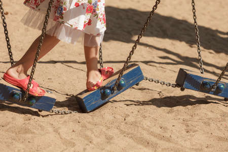 Active kids, outdoor fun concept. Little toddler girl in floral dress playing outside on playground...