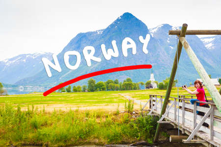 Tourism vacation and travel. Woman tourist relaxing on bridge, looking at mountains landscape in norwegian village Oppstryn, Sogn og Fjordane county. Norway Scandinavia.の写真素材