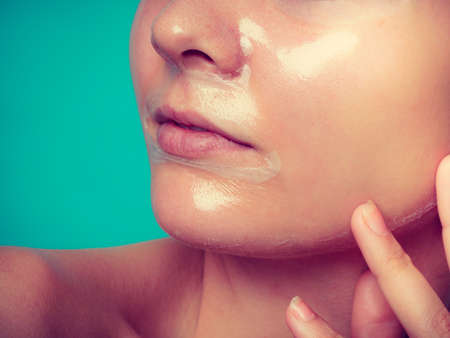Close up young woman in facial peel off mask, part of face. Peeling. Wellness and skincare.の写真素材