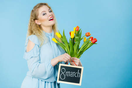 International womens day. Beautiful woman blonde hair fashion make up holding red yellow tulips and...