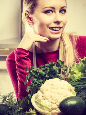 Young woman in kitchen having many green vegetables about to cook something healthy and vegetarianの写真素材