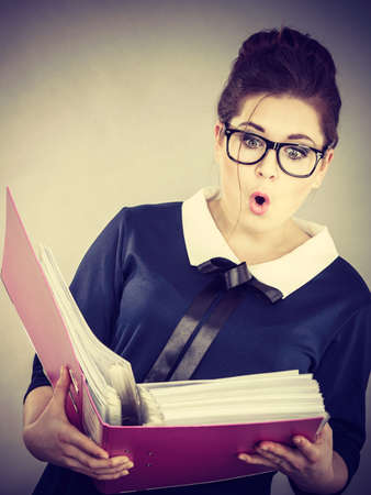 Shocked accountant business woman looking at documents in binder seeing something surprisingの写真素材