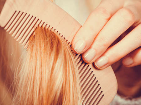 Haircare, choosing best conditioner for tangled hairstyle concept. Blonde woman brushing her hair with combの写真素材