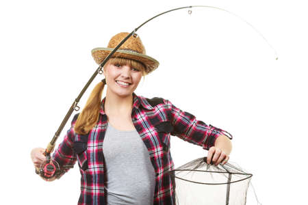 Spinning, angling, cheerful fisherwoman concept. Happy woman in sun hat holding fishing rod and keepnet having fun.の写真素材