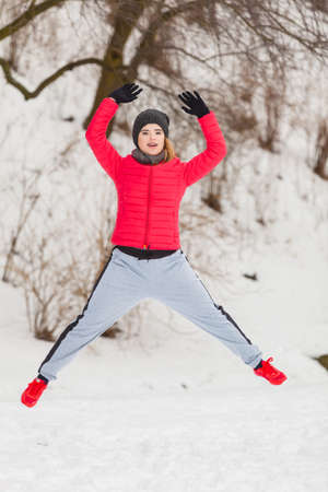 Outdoor sport exercising, sporty outfit ideas. Woman wearing warm sportswear training exercising outside during winter, jumping out of joy.の写真素材
