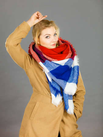 Woman wearing light brown coat and colorful checked scarf. Winter fashion concept.の写真素材