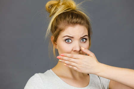Woman covering her mouth with hand. Seeing something shocking, surprised and speechless face...