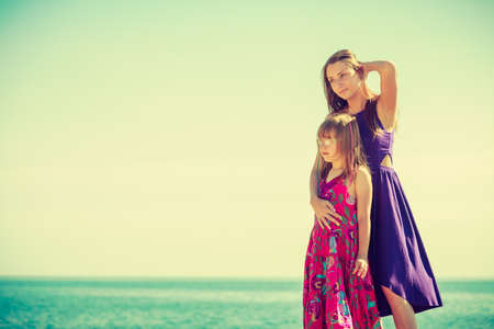 Woman and girl posing at rocks with water in backgroundの写真素材