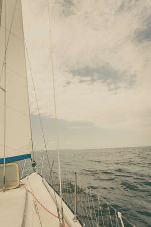 Yachting on sail boat during sunny summer weather on calm blue sea water. Sporty transportation conept.の写真素材
