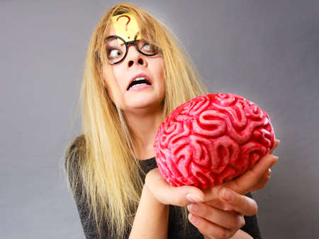 Weird blonde woman holding brain having something on mind, thinking of idea.の写真素材