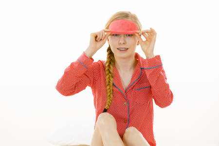 Sleep bedroom accessories concept. Happy sleepy woman wearing pink eye band and pajamas.の写真素材