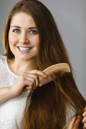 Haircare and morning hairstyling concept. Happy woman brushing her long dark brown hair