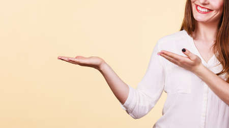 Woman showing presenting, long haired fashionable girl holding empty hand palm copy space for product. Beauty, fashion, advertisement concept. Studio shot on bright backgroundの写真素材